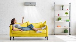 Attractive-young-girl-lying-on-yellow-sofa-under-air-conditioner-at-home-min-e1685398329545.jpeg