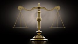 A_dramtically_lit_gold_justice_scale_backlit_an_a_dark_background.jpeg