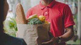 Delivery_service_man_in_red_uniform_handing_fresh_food_to_recipient.jpeg