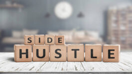 Side hustle sign on a plank table in a decorative room with a clock