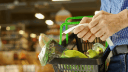 A_shopper_checks_his_grocery_list_while_carrying_a_basket_full_of_fresh_items.png