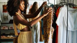 medium-shot-of-woman-looking-at-dress-while-shopping-in-boutique